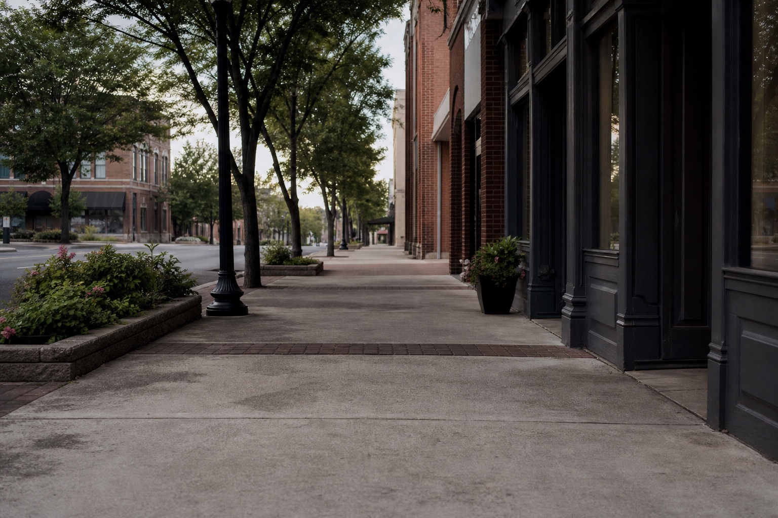 A quiet Harrison-inspired downtown sidewalk lined with brick storefronts and trees